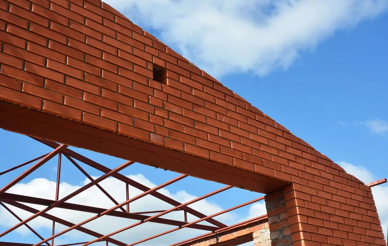 A brick wall with a metal roof and sky background